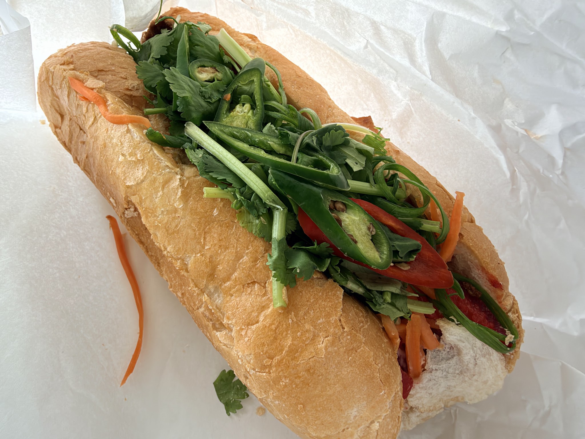 A bánh mì packed with fresh coriander, chilli and pickled carrot