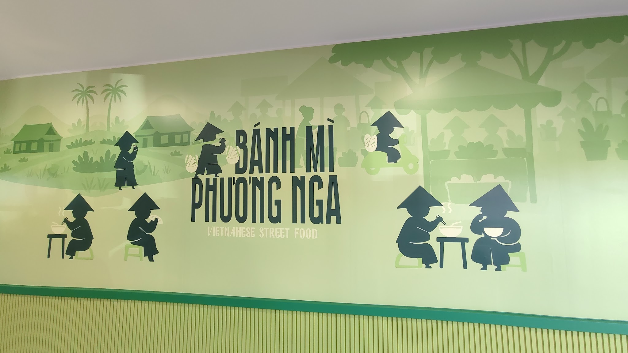 The mural inside the shop: a Vietnamese street-food scene with conical hats, low stools and bowls of noodles